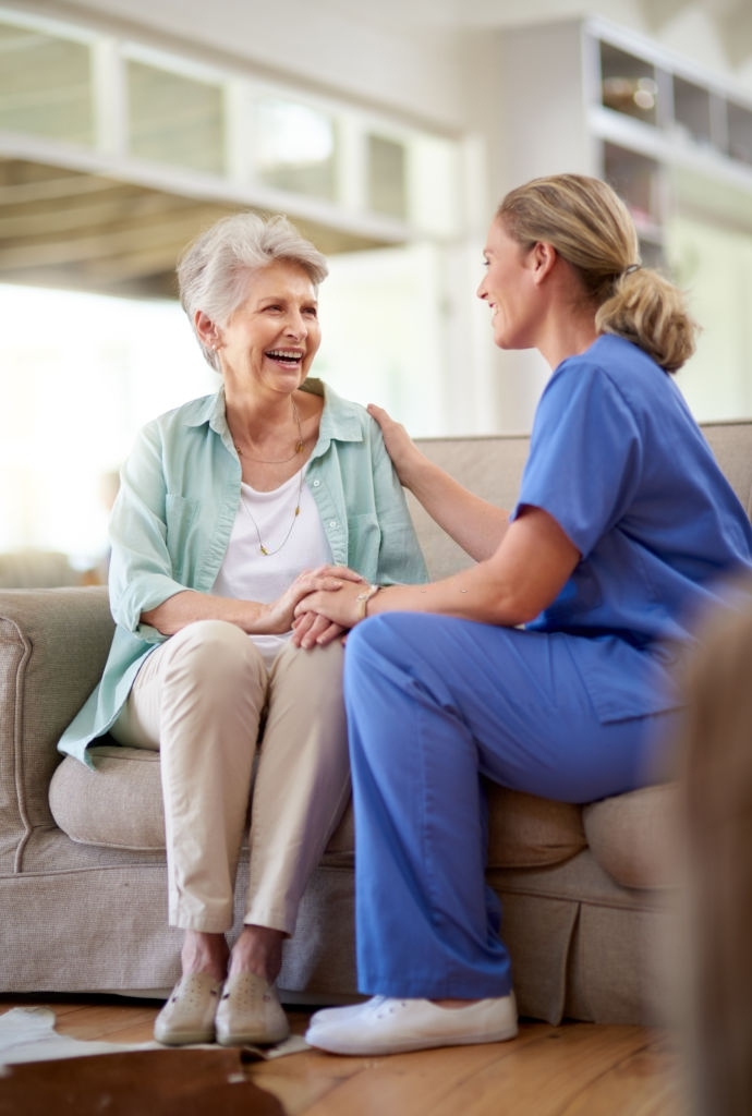 an elderly woman talking to a female medical professional in blue scrubs