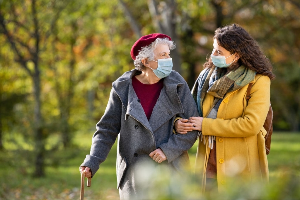 a young woman and an elderly woman taking a walk and both wearing masks
