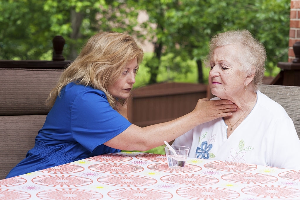 a woman wearing blue checking how the elderly woman swallows