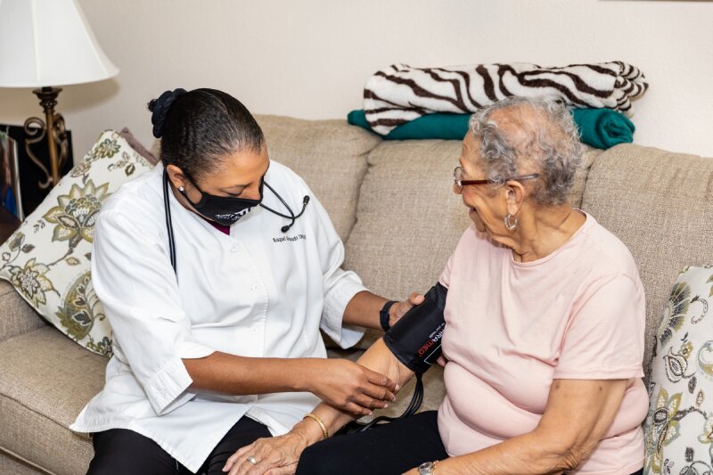 a female medical professional checking the blood pressure of an elderly woman